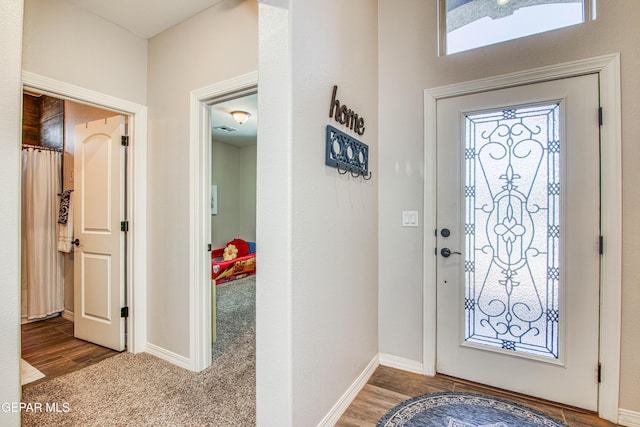 carpeted foyer featuring baseboards and visible vents