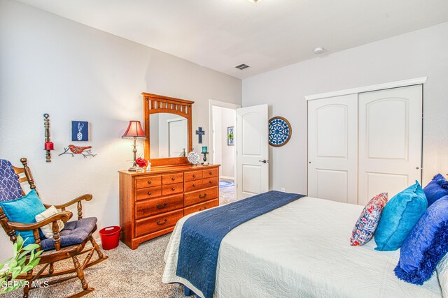 carpeted bedroom with visible vents and a closet