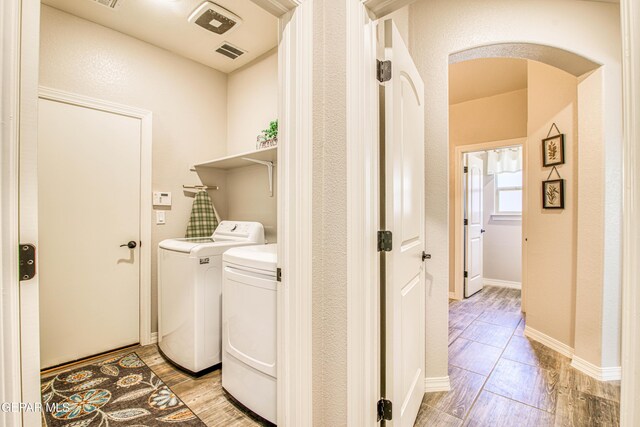 clothes washing area featuring laundry area, visible vents, washer and clothes dryer, and light wood-style floors