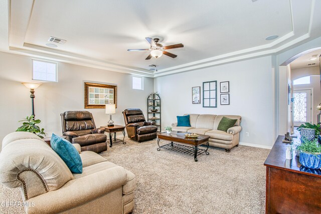 living room featuring arched walkways, a tray ceiling, visible vents, and ceiling fan