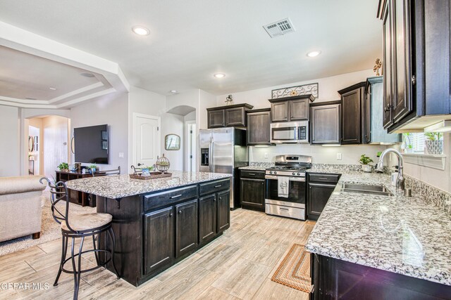 kitchen with visible vents, a sink, a kitchen breakfast bar, arched walkways, and appliances with stainless steel finishes
