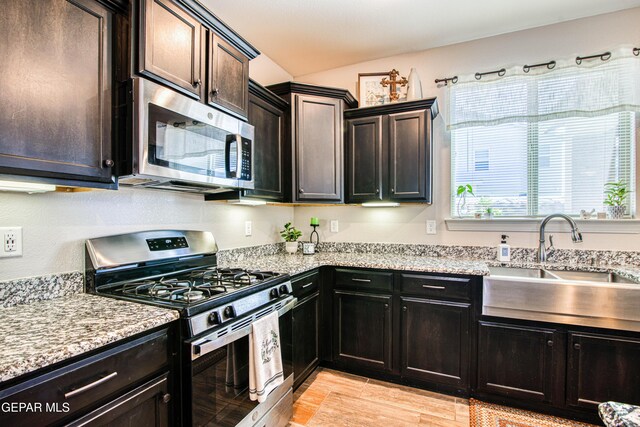 kitchen featuring a sink, light wood-style flooring, appliances with stainless steel finishes, and light stone countertops