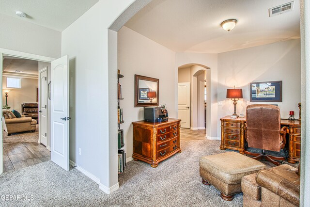 carpeted office space featuring arched walkways, baseboards, and visible vents
