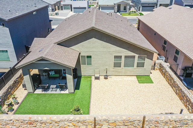 rear view of house featuring a fenced backyard, a shingled roof, stucco siding, and a patio area