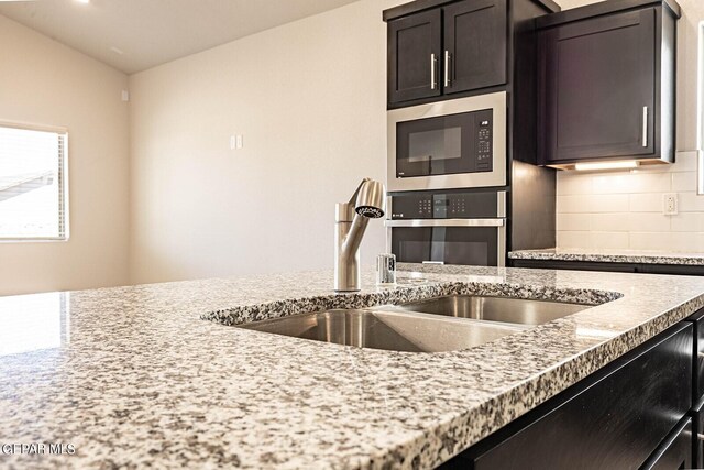 3817 Course St, El Paso, TX 79938 - kitchen with decorative backsplash, light stone countertops, oven, built in microwave, and a sink