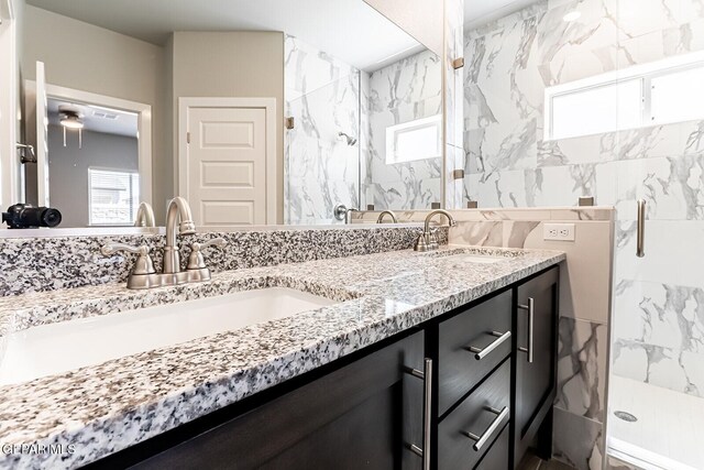 bathroom with double vanity, a sink, and a marble finish shower