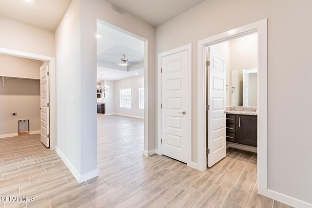 hall featuring baseboards, wood finish floors, and a chandelier