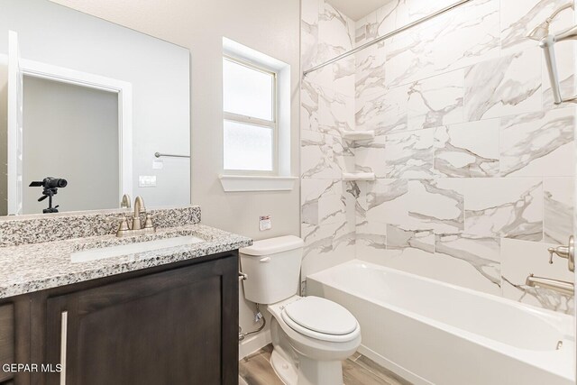 bathroom featuring toilet, tub / shower combination, wood finished floors, and vanity
