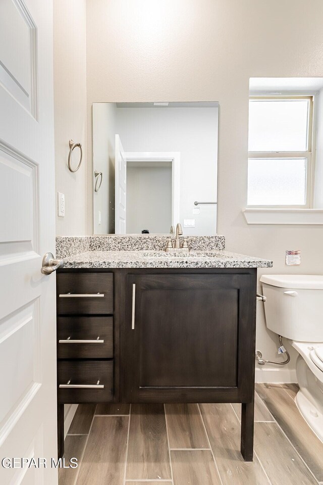 bathroom with toilet, wood finished floors, and vanity