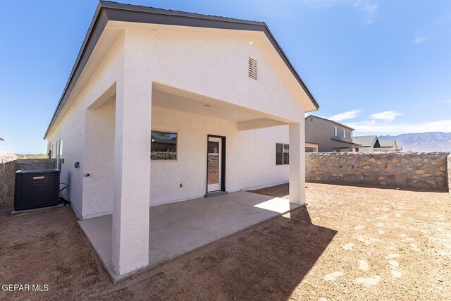 rear view of property with stucco siding, a fenced backyard, a mountain view, cooling unit, and a patio area