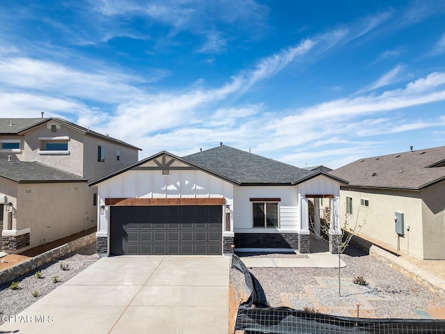 view of front facade featuring a garage, roof with shingles, stone siding, and concrete driveway