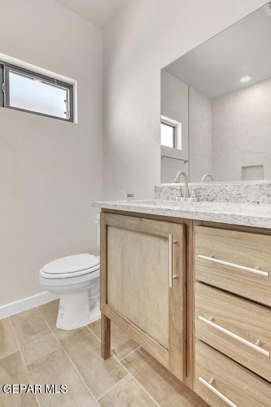 bathroom with a healthy amount of sunlight, vanity, baseboards, and toilet