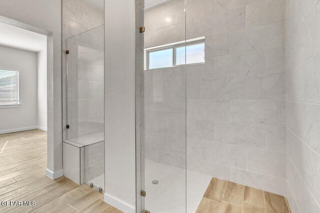 full bathroom featuring baseboards, wood finished floors, and a shower stall