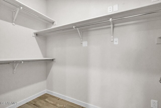 walk in closet with wood finish floors