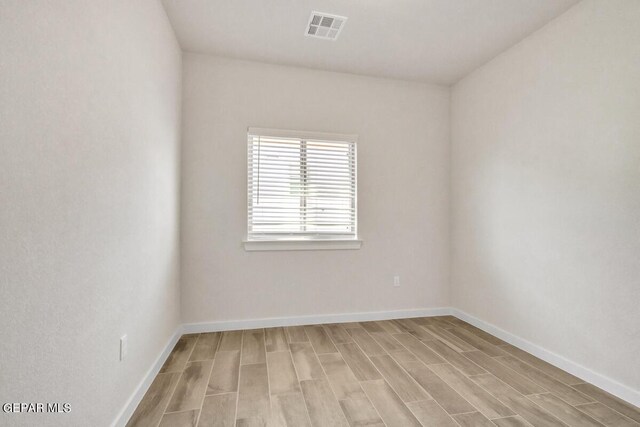 empty room with visible vents, baseboards, and wood finish floors