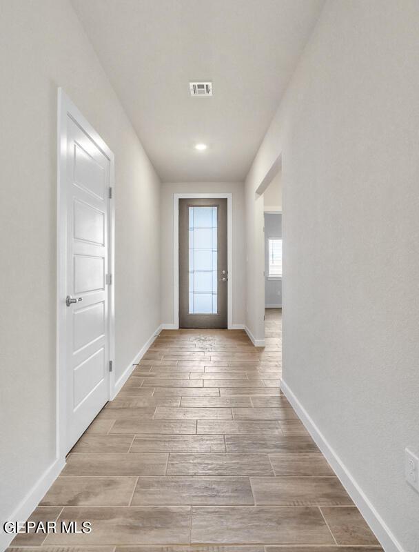 doorway to outside with baseboards, visible vents, and wood finished floors