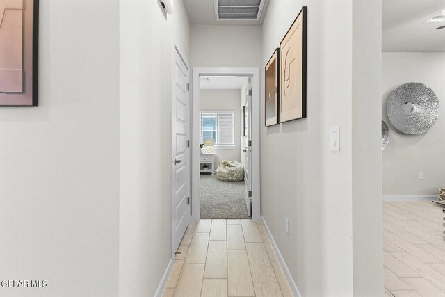 hall featuring baseboards, visible vents, and wood tiled floor