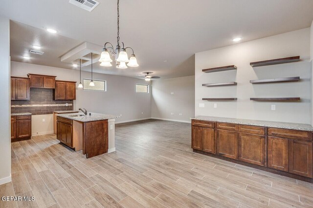 kitchen with visible vents, open shelves, brown cabinetry, pendant lighting, and a sink