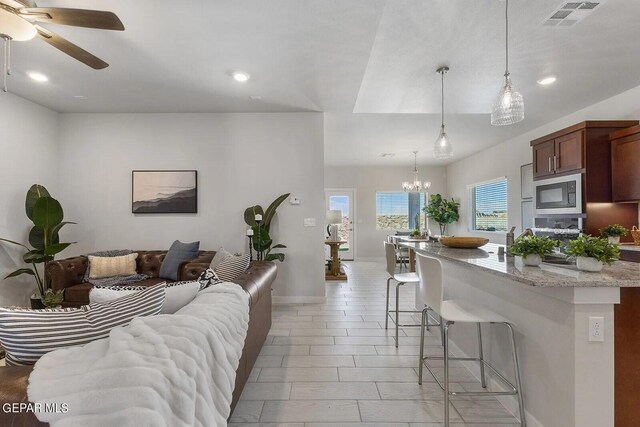 living area featuring visible vents, recessed lighting, baseboards, and ceiling fan with notable chandelier