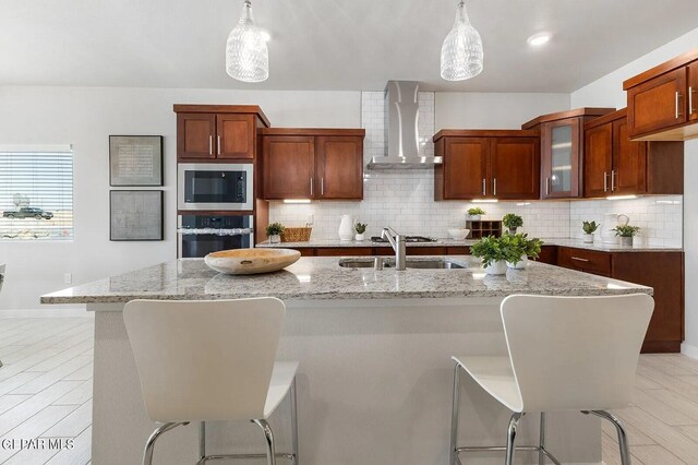 kitchen with oven, wall chimney range hood, built in microwave, light stone counters, and a sink