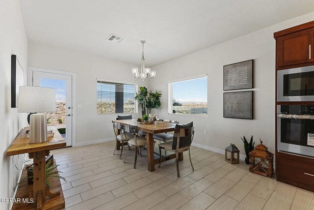 dining area with an inviting chandelier, light wood finished floors, baseboards, and visible vents