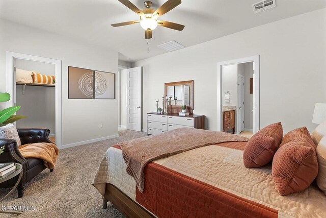 bedroom with light colored carpet, a walk in closet, baseboards, visible vents, and a closet