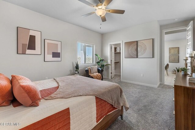carpeted bedroom featuring baseboards, a ceiling fan, and a spacious closet