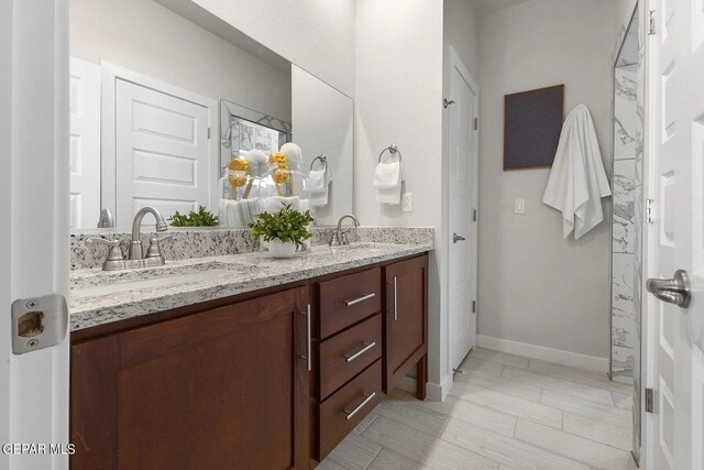 full bath with double vanity, a sink, and baseboards