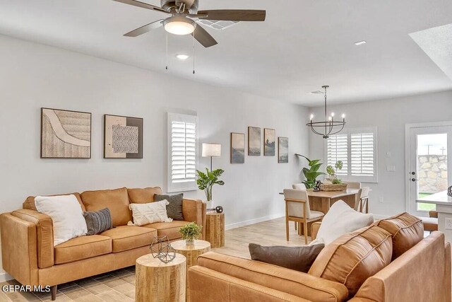 living room featuring baseboards, ceiling fan with notable chandelier, and light wood-style floors