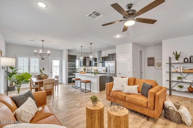 living room featuring visible vents, recessed lighting, light wood finished floors, and ceiling fan with notable chandelier