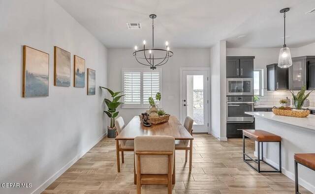 dining area with baseboards, wood finish floors, a chandelier, and visible vents