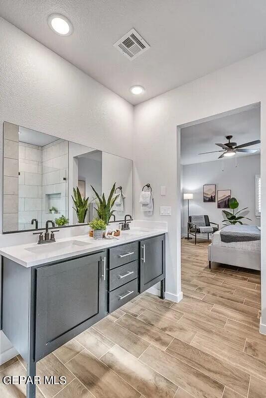 bathroom with double vanity, wood finish floors, a sink, and visible vents
