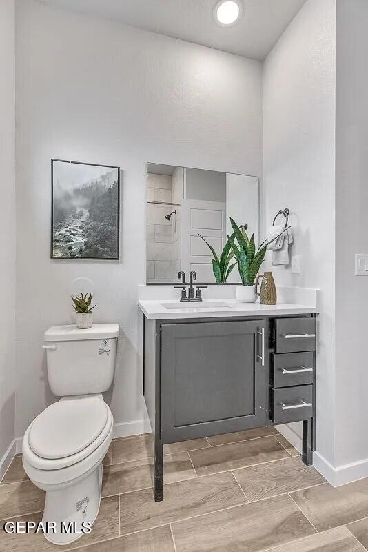 bathroom featuring toilet, baseboards, wood finish floors, and vanity