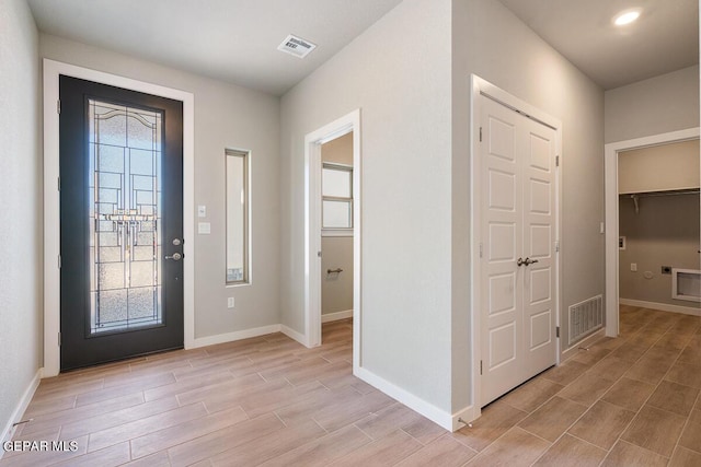 foyer entrance featuring baseboards, visible vents, and light wood-type flooring