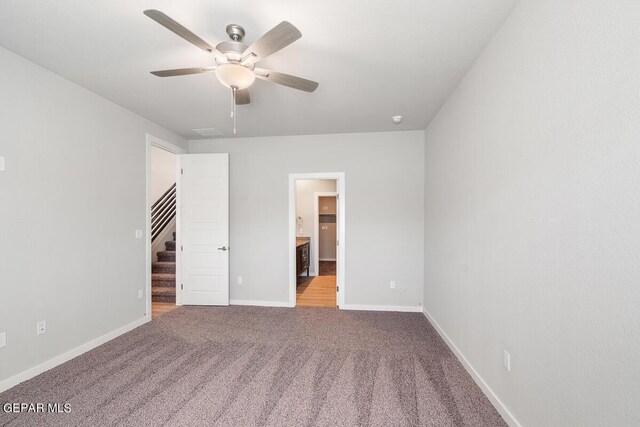 unfurnished bedroom with baseboards, a ceiling fan, carpet flooring, and connected bathroom