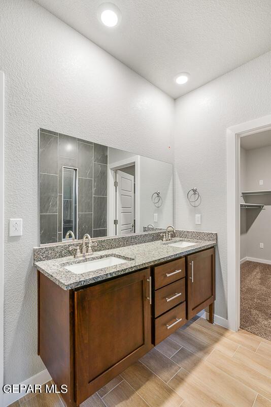 bathroom with double vanity, baseboards, a sink, and wood finished floors
