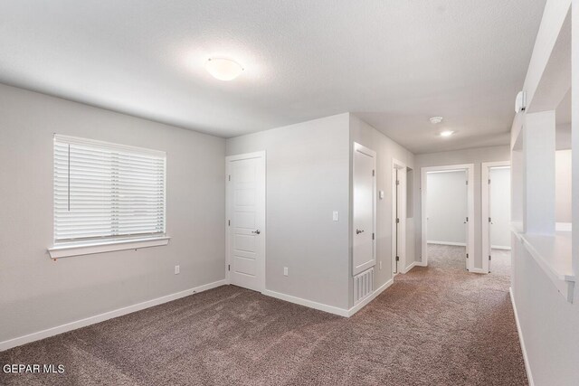unfurnished bedroom with carpet floors, baseboards, and a textured ceiling