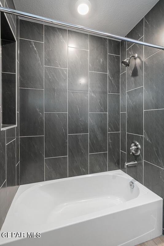 bathroom with a textured ceiling and washtub / shower combination