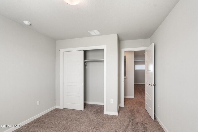 unfurnished bedroom with baseboards, carpet, and a closet