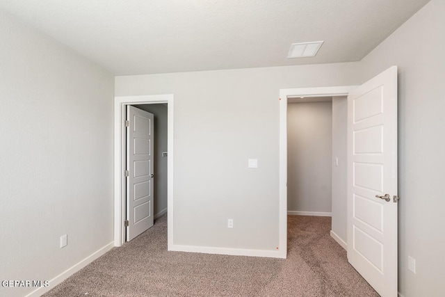 unfurnished bedroom featuring baseboards, visible vents, and carpet