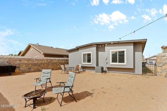 rear view of property featuring cooling unit, a fenced backyard, stucco siding, a patio area, and an outdoor fire pit