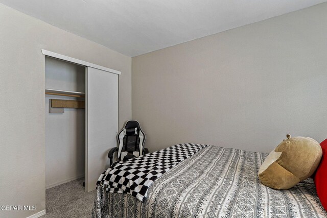 carpeted bedroom featuring baseboards and a closet