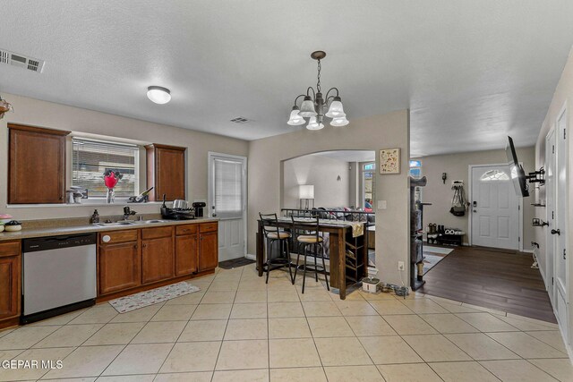 kitchen with visible vents, light countertops, arched walkways, a sink, and dishwasher