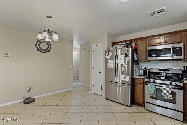 kitchen with light tile patterned flooring, appliances with stainless steel finishes, an inviting chandelier, baseboards, and visible vents
