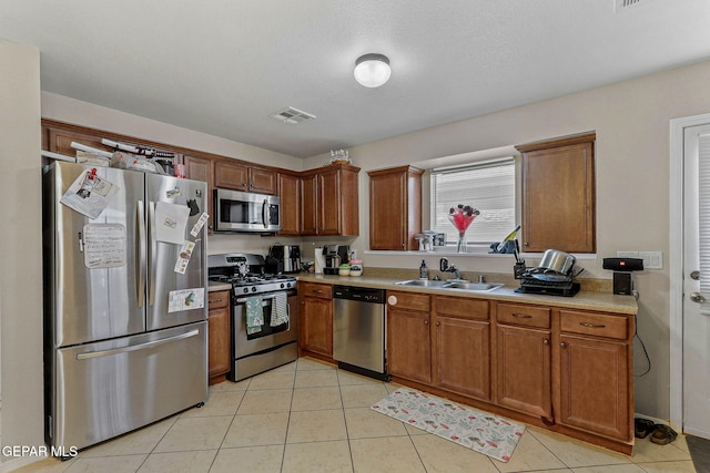 kitchen featuring visible vents, brown cabinets, a sink, light countertops, and stainless steel appliances