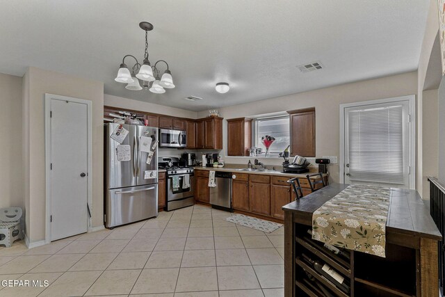 kitchen with visible vents, appliances with stainless steel finishes, hanging light fixtures, light tile patterned floors, and a notable chandelier