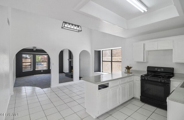 kitchen featuring a peninsula, open floor plan, arched walkways, and black range with gas stovetop