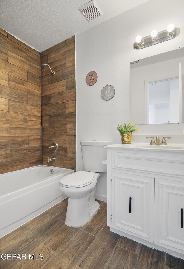 full bathroom with visible vents, wood finished floors, vanity, toilet, and washtub / shower combination