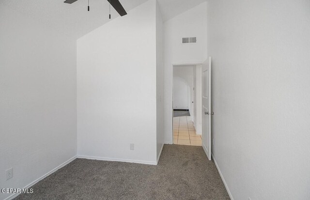 empty room featuring visible vents, carpet flooring, baseboards, high vaulted ceiling, and a ceiling fan