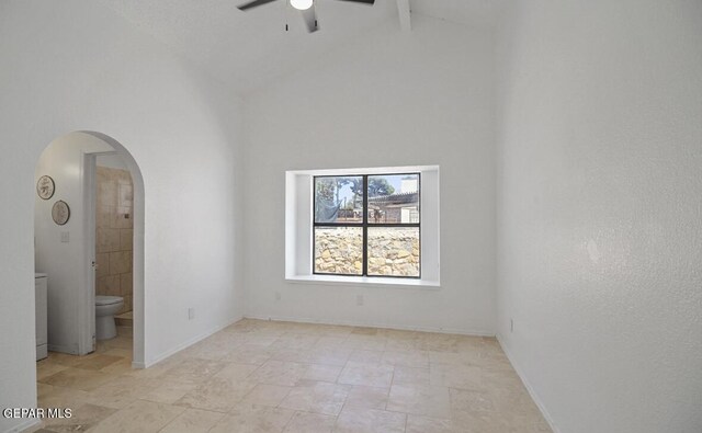 unfurnished bedroom featuring beamed ceiling, baseboards, high vaulted ceiling, arched walkways, and ensuite bath